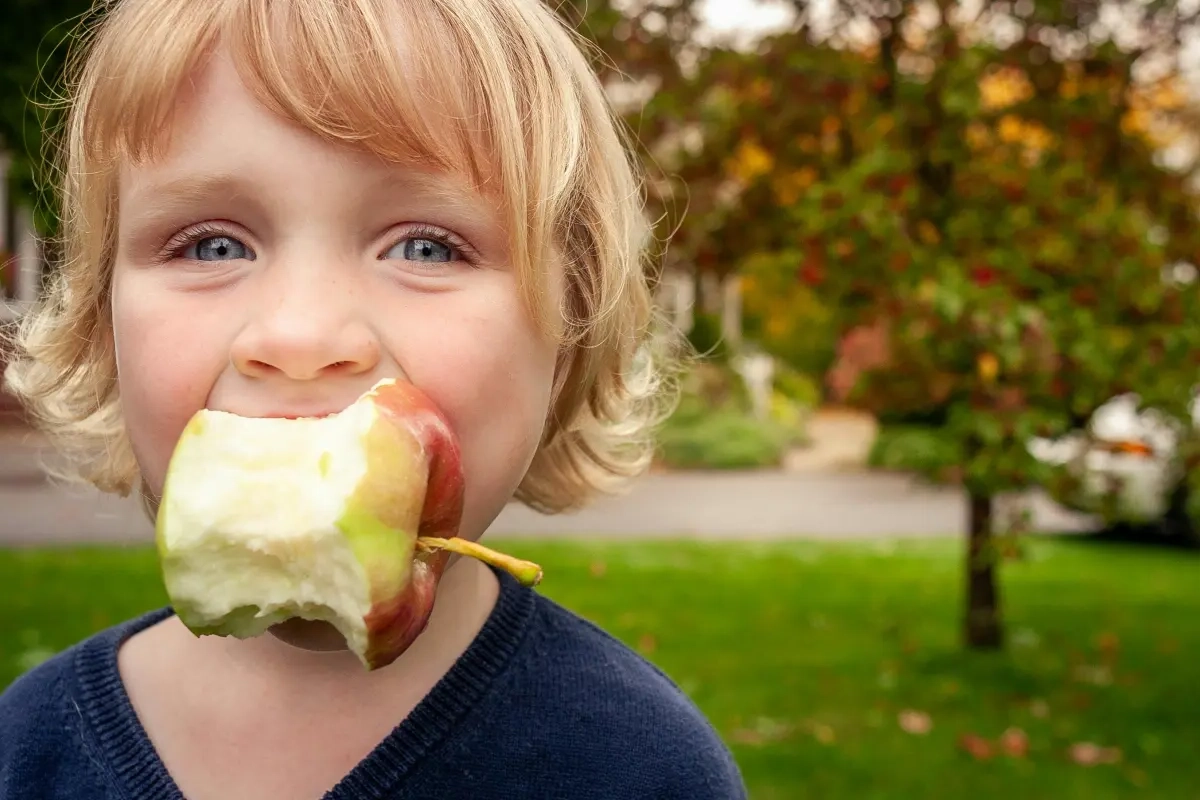 Kind mit angebissenem Apfel im Mund