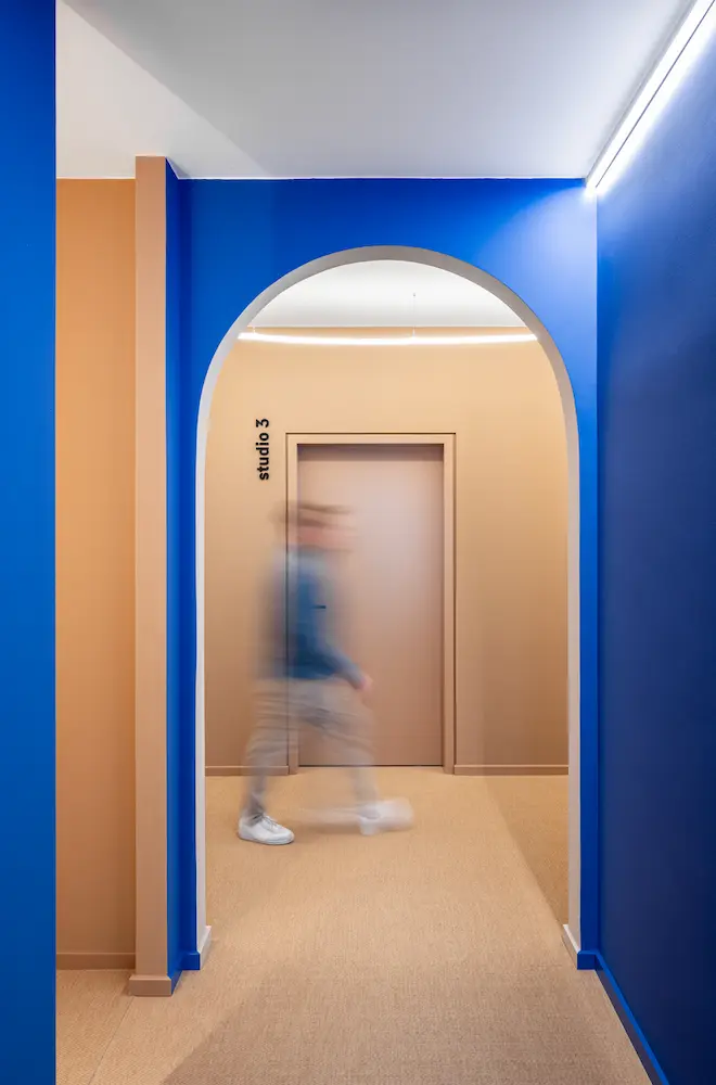 Ein verschwommener Mensch geht durch einen gewölbten Durchgang mit kräftig blauen Wänden in einer modernen Praxis in Oberhaching.